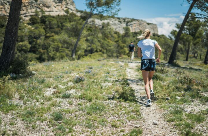 Frau joggt allein auf einem Bergpfad – Symbol für innere Stärke und nachhaltige Sportmotivation